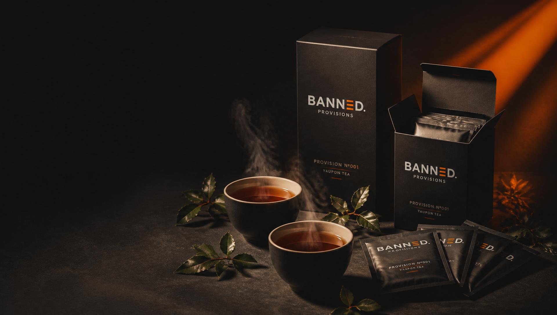 Banned Provisions Provision №001 yaupon tea carton, opened box with foil sachets, and two ceramic cups of amber brewed tea on a dark surface